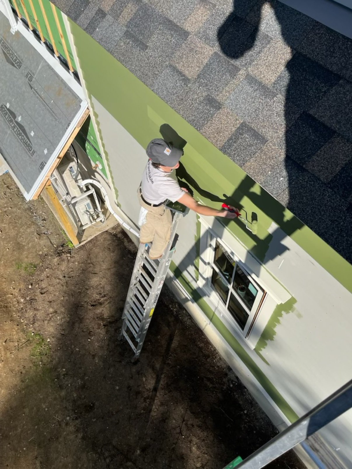 Paintable painter rolling fresh paint on Vermont home siding